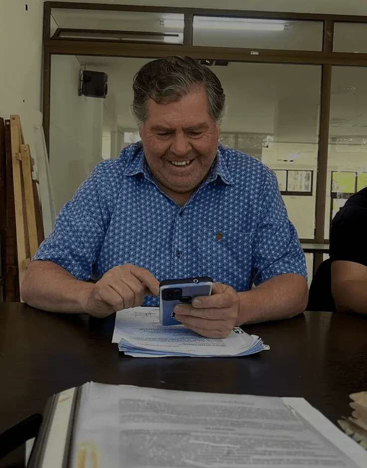 Integrante del sindicato sonriendo mientras revisa su teléfono en la oficina