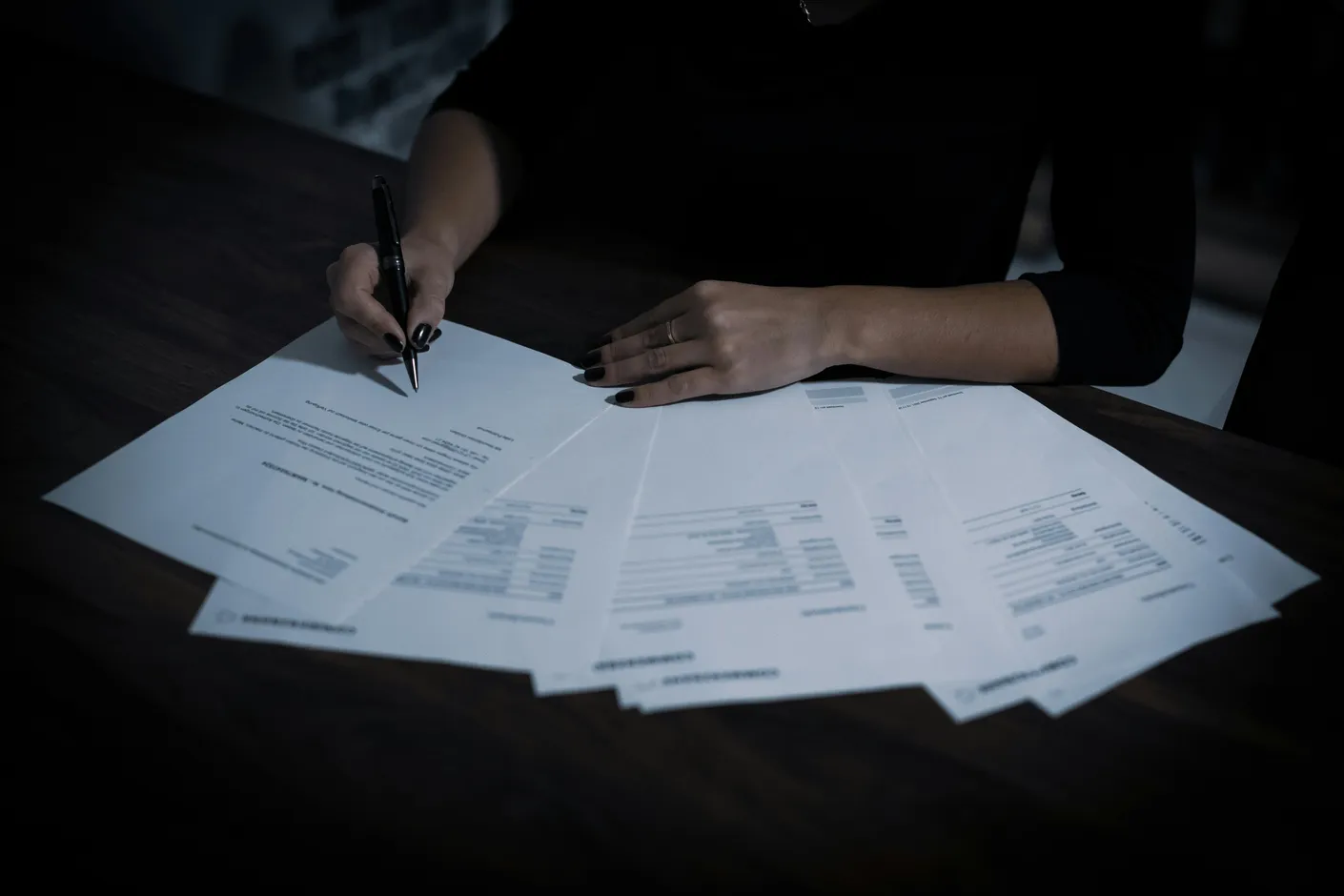 Persona firmando documentos sobre una mesa